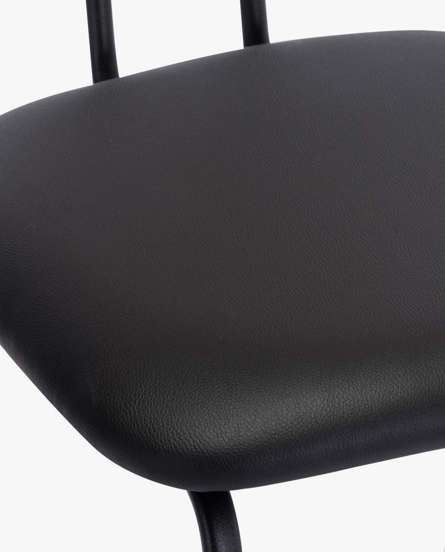 Close-up of the chair seat shows black textured upholstery on a curved seat pan with metal leg